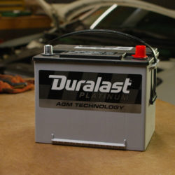 Duralast Platinum battery on a shop table in front of an open Nissan Altima.