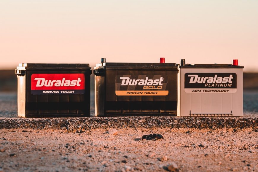 All three tiers of Duralast batteries sitting on top of the edge of a road in the desert.