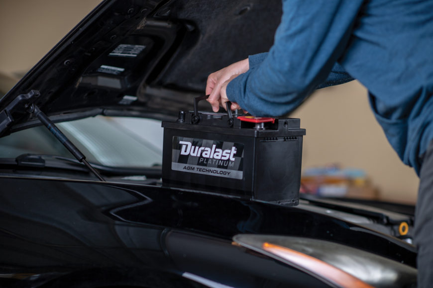Man putting Duralast Platinum automotive battery in vehicle