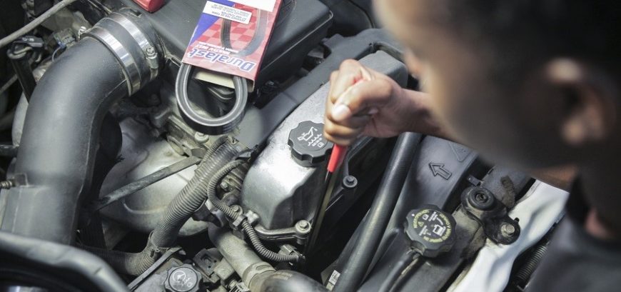 A person using a serpentine belt tool to loosen and remove the old belt before installing a new one.