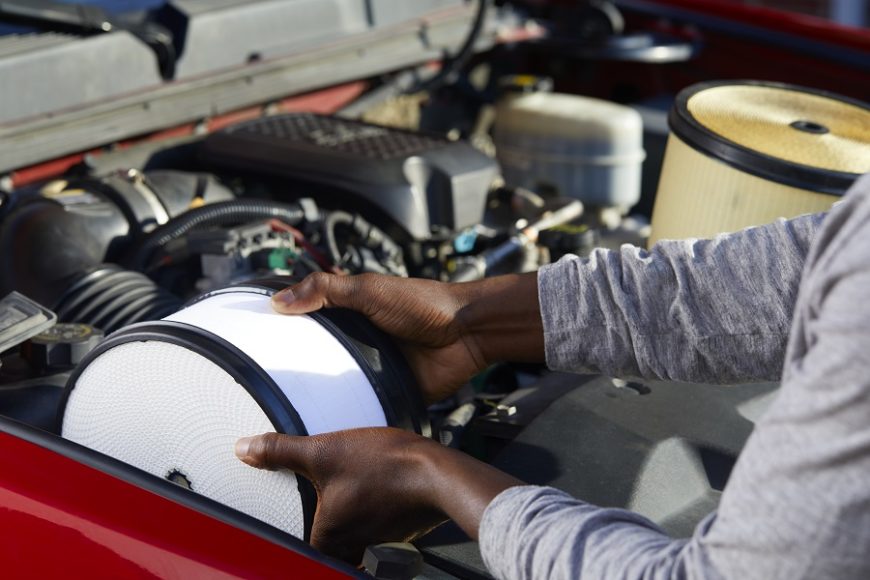 Man showing one step of how to install an air filter by placing it into the car.