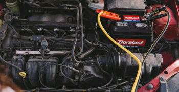 Jumper cables connected to the posts of a Duralast battery inside of a car