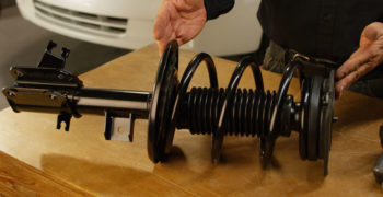 A Duralast loaded strut sitting on top of a shop table.