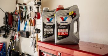 Two bottles of Valvoline full synthetic oil, one high mileage the other advanced, sitting on top of a red tool box in a garage.