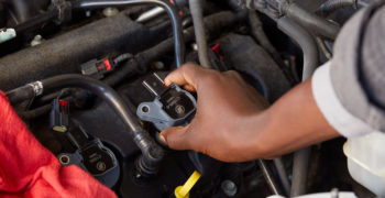 a hand holding an ignition coil to demonstrate it's location