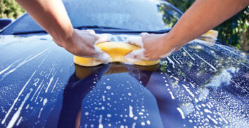 yellow sponge washing blue car with car wash suds