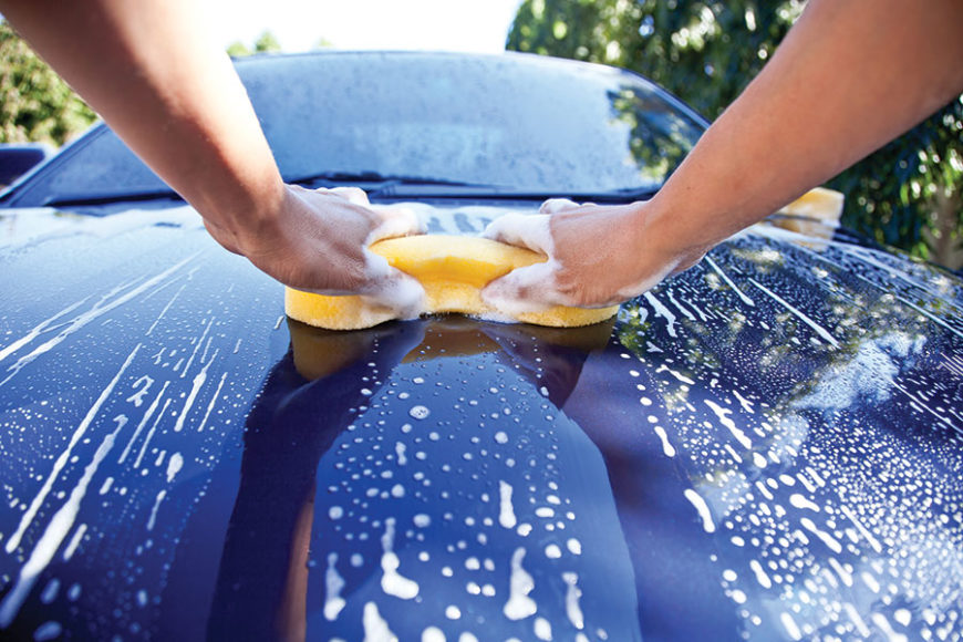 yellow sponge washing blue car with car wash suds