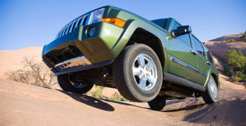 Jeep driving over rugged terrain using coil spring suspension. These same jeeps are also available with leaf springs.