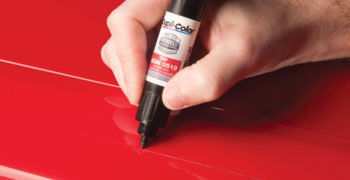 person demonstrating how to use car paint touch up on a red vehicle.