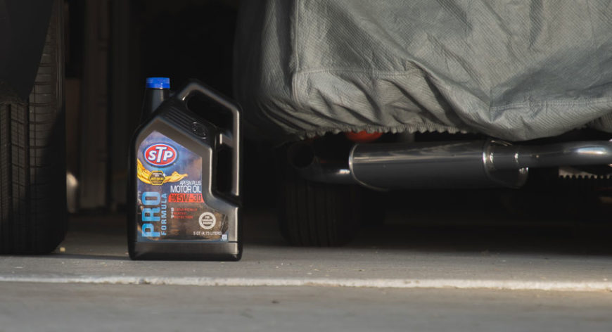 Jug of motor oil sitting between two cars in the garage