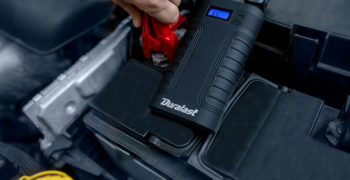 Person using a Duralast battery booster to jump start a car