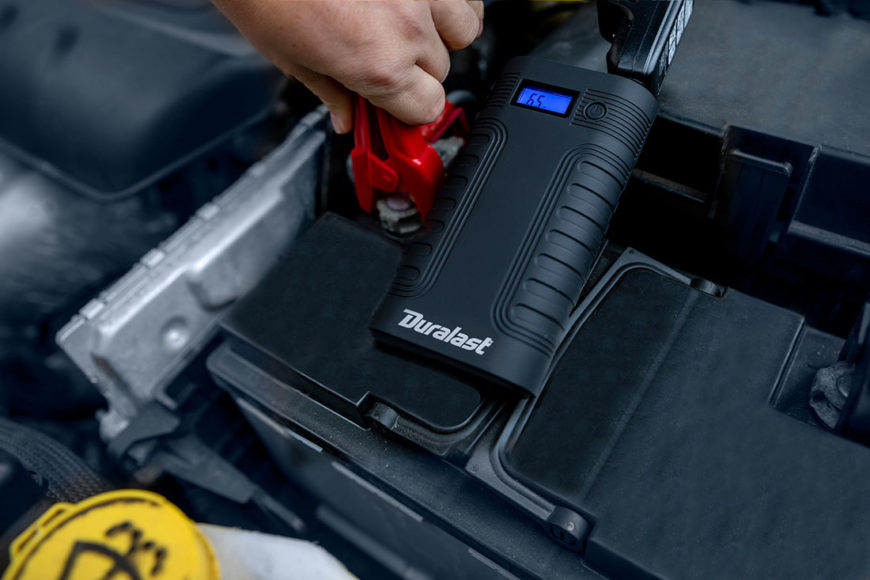 Person using a Duralast battery booster to jump start a car
