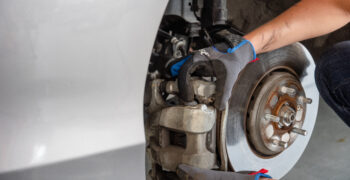 removing brake caliper from car with duralast gloves on 1